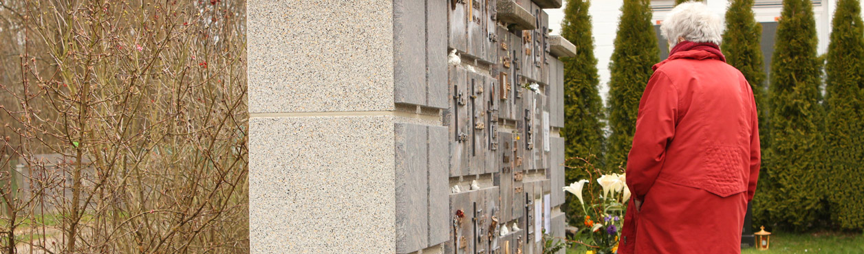 Trauernde Frau vor halbanonymen Urnengräbern